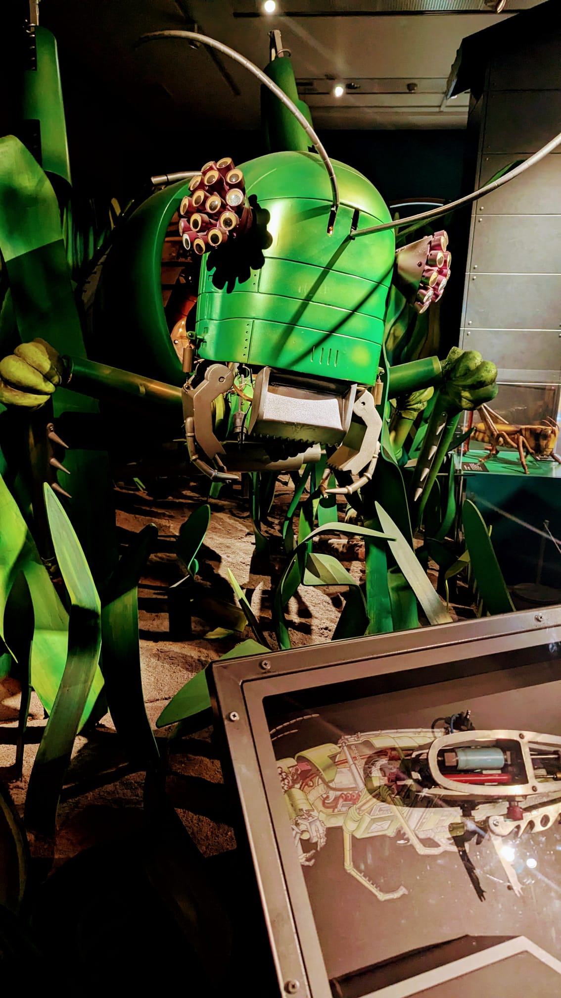 Green robot-like creature with a screen displaying a design on a dark background