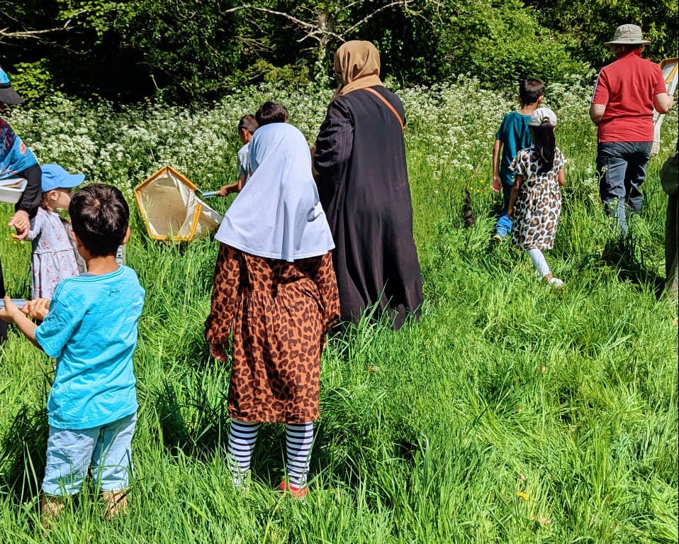 Group of people in a grassy field with one person holding a large net.