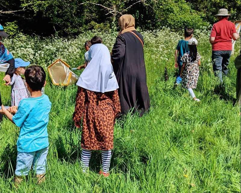 Group of people in a grassy field with one person holding a large net.