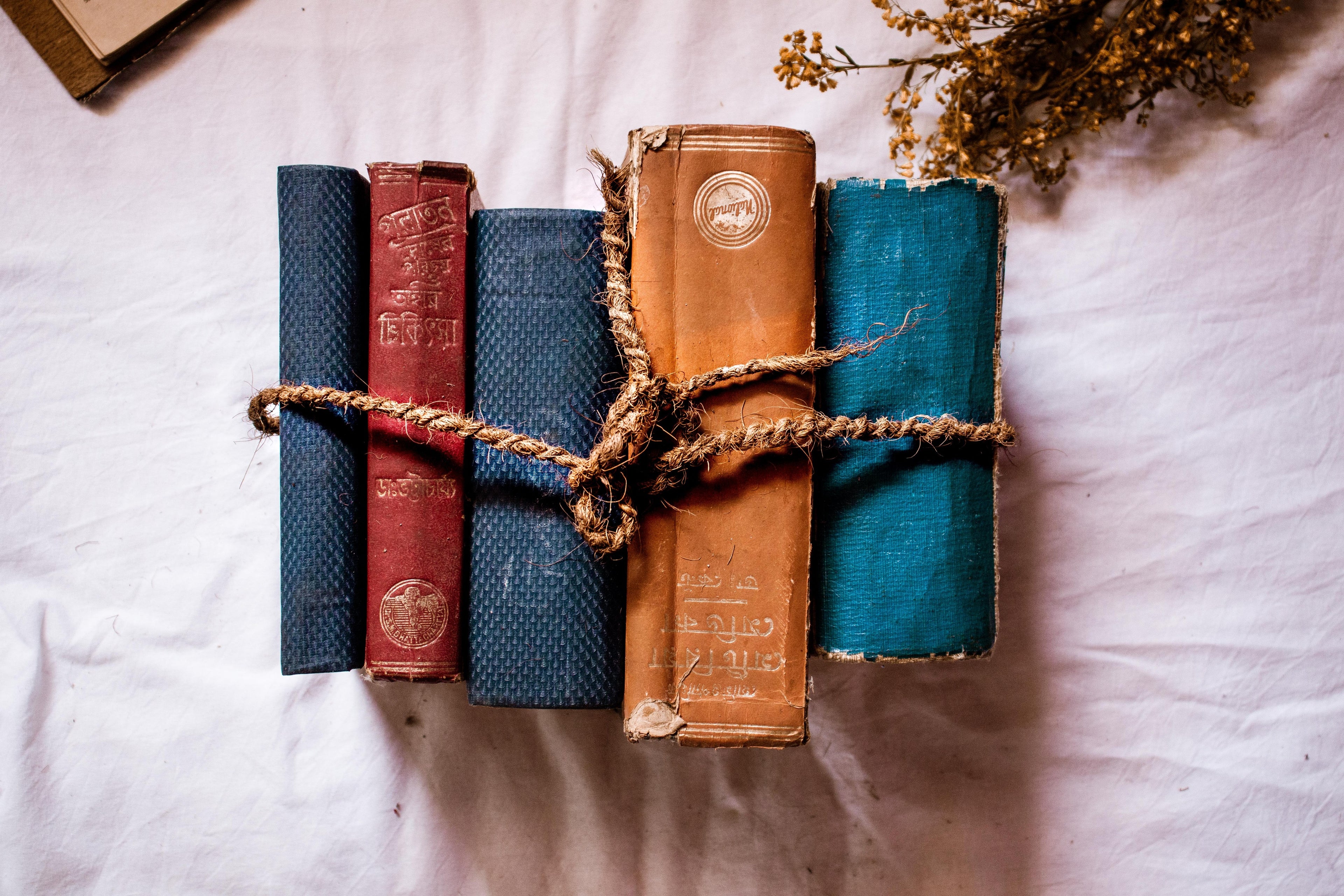 books-bound-together-with-twine-on-a-white-cloth